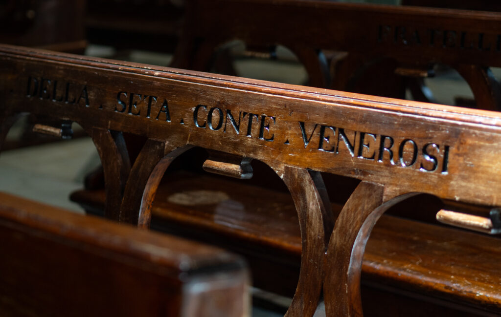 Close-up van een oude kerkbank met gegraveerde tekst – symbolisch beeld voor herinnering, betekenis en de kracht van verhalen die blijven.