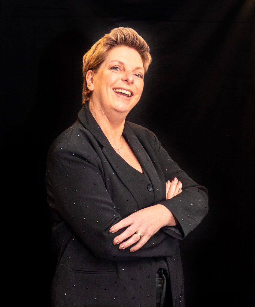 Zakelijk portret van een vrouwelijke stylist met open houding en warme uitstraling, gefotografeerd in natuurlijke belichting.