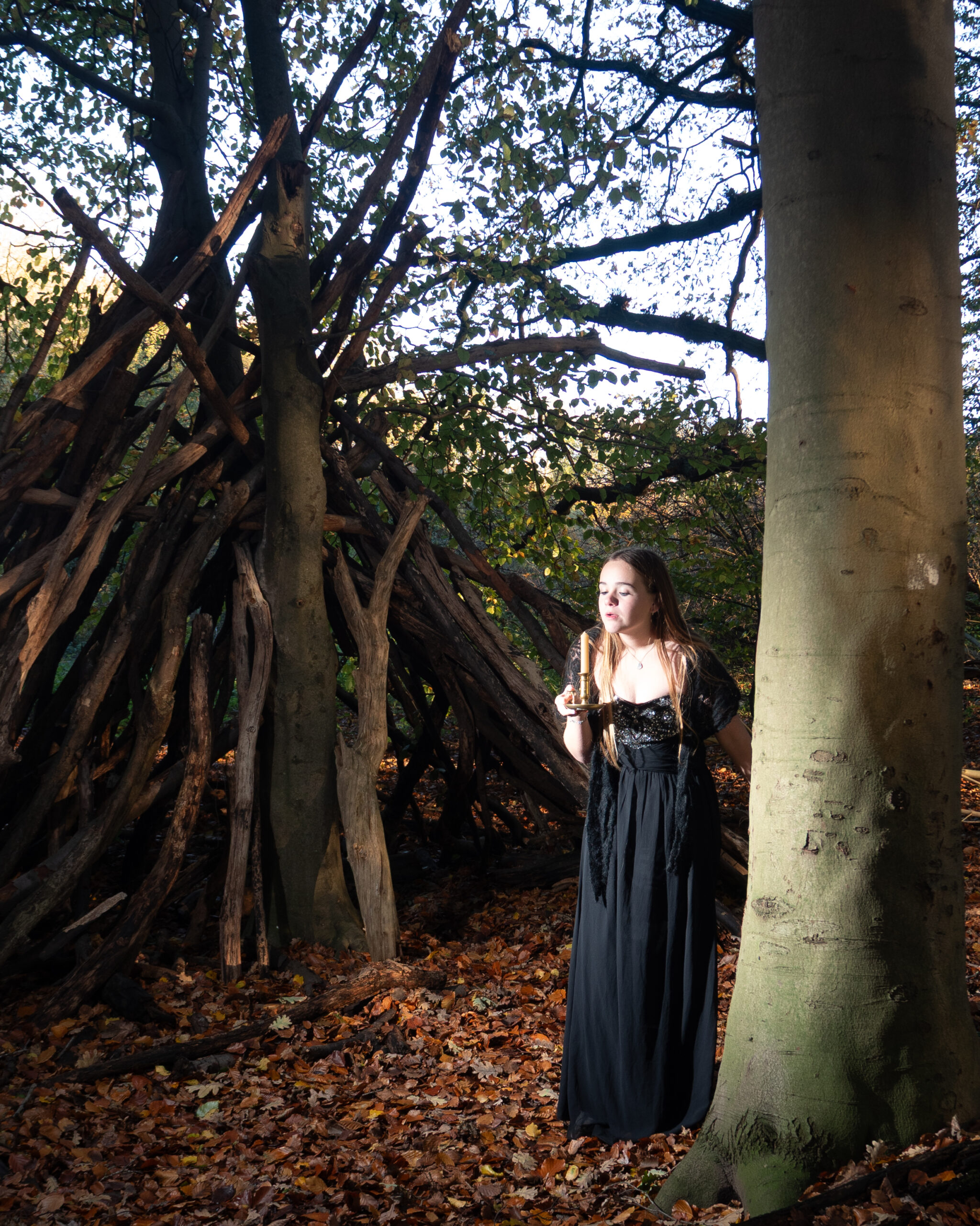 Creatieve foto van meisje dat een kaars uitblaast in het bos – symbool voor storytelling en het overbrengen van emotie.”